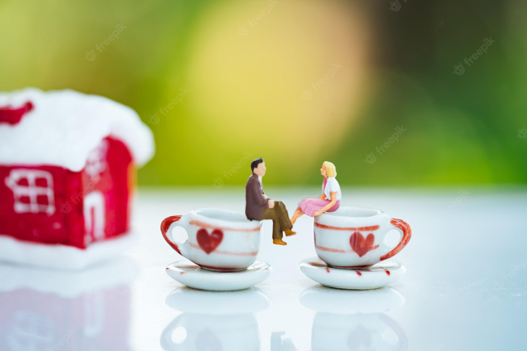 2000x1334 Premium Photo. Small couple figure in love on coffee cup with red house