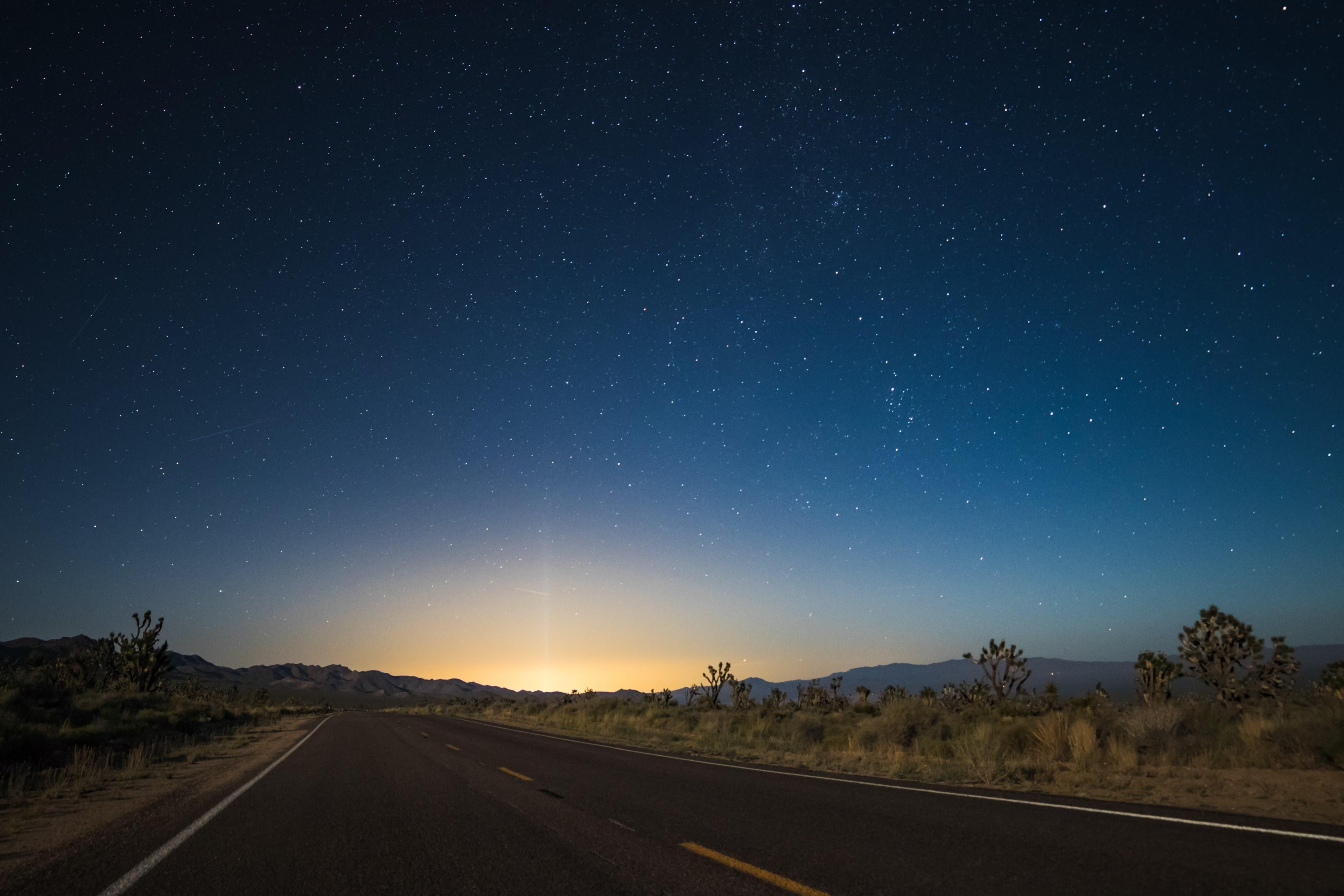 3840x2560 Wallpaper / the pavement in the center of desert area leads to glowing sunrise illuminating night sky, starry sky transition at nipton 4k wallpaper free download