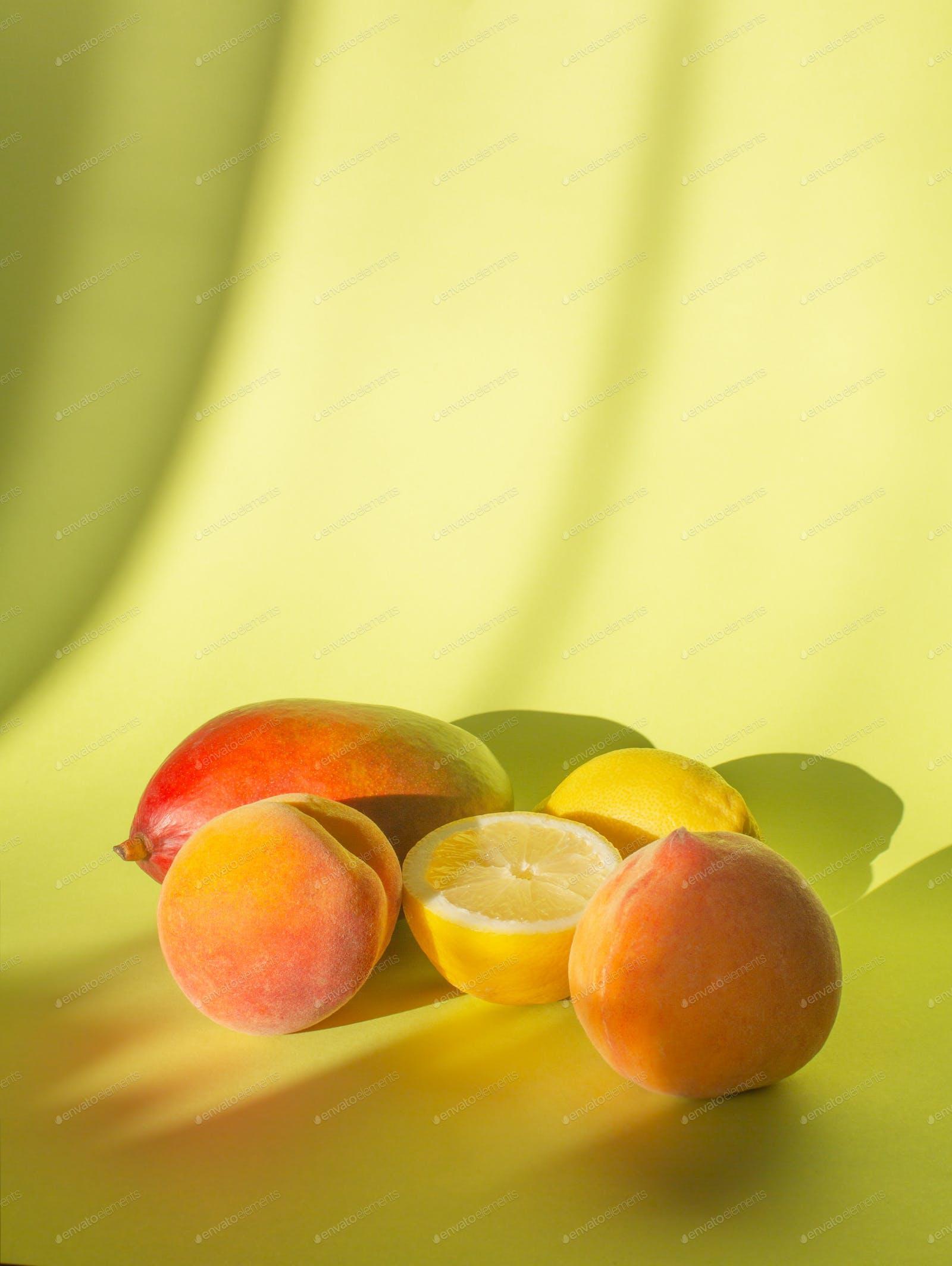 1600x2128 Fresh peaches, lemon and mango on a pastel background with shadows photo by Civil on Envato Elements