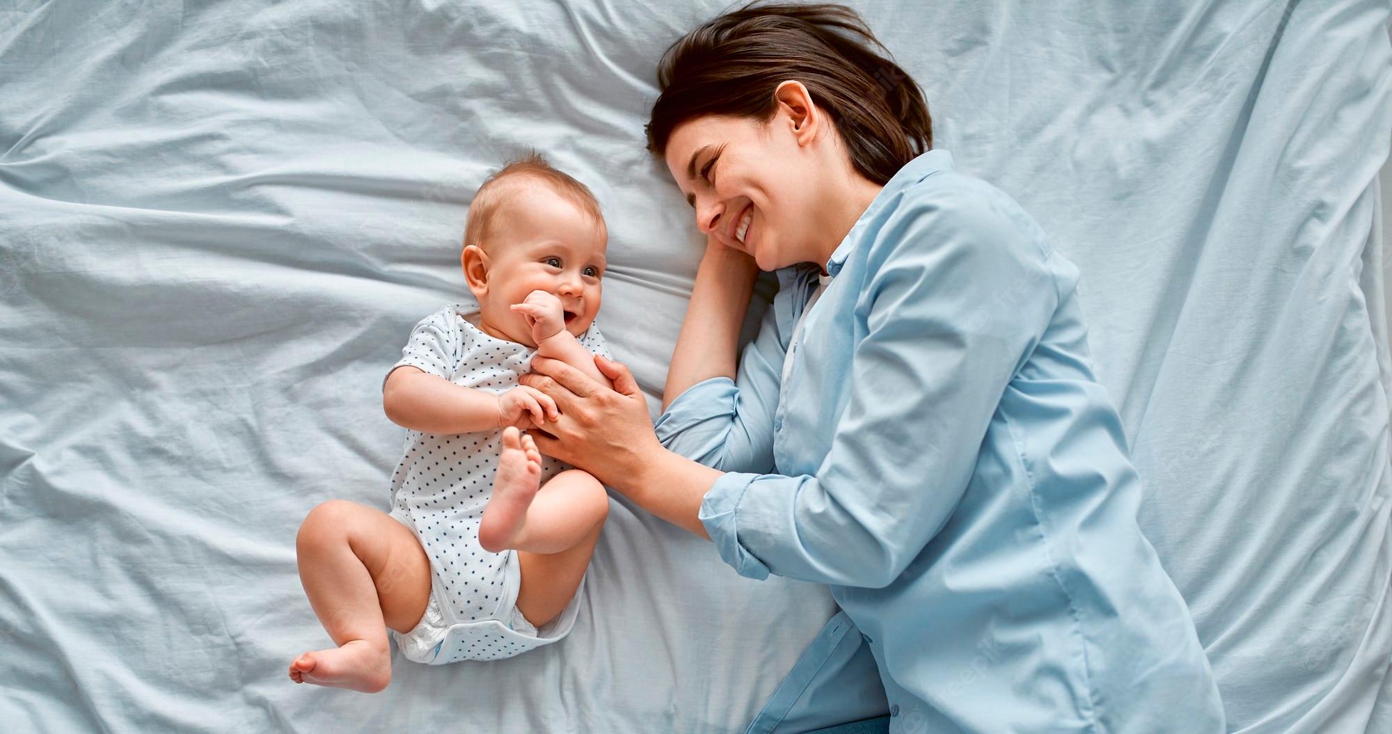 2000x1055 Premium Photo. Loving mom carying of her newborn baby at home.mom and baby boy playing in sunny bedroom. parent and little kid relaxing at home. family having fun together. childcare, maternity