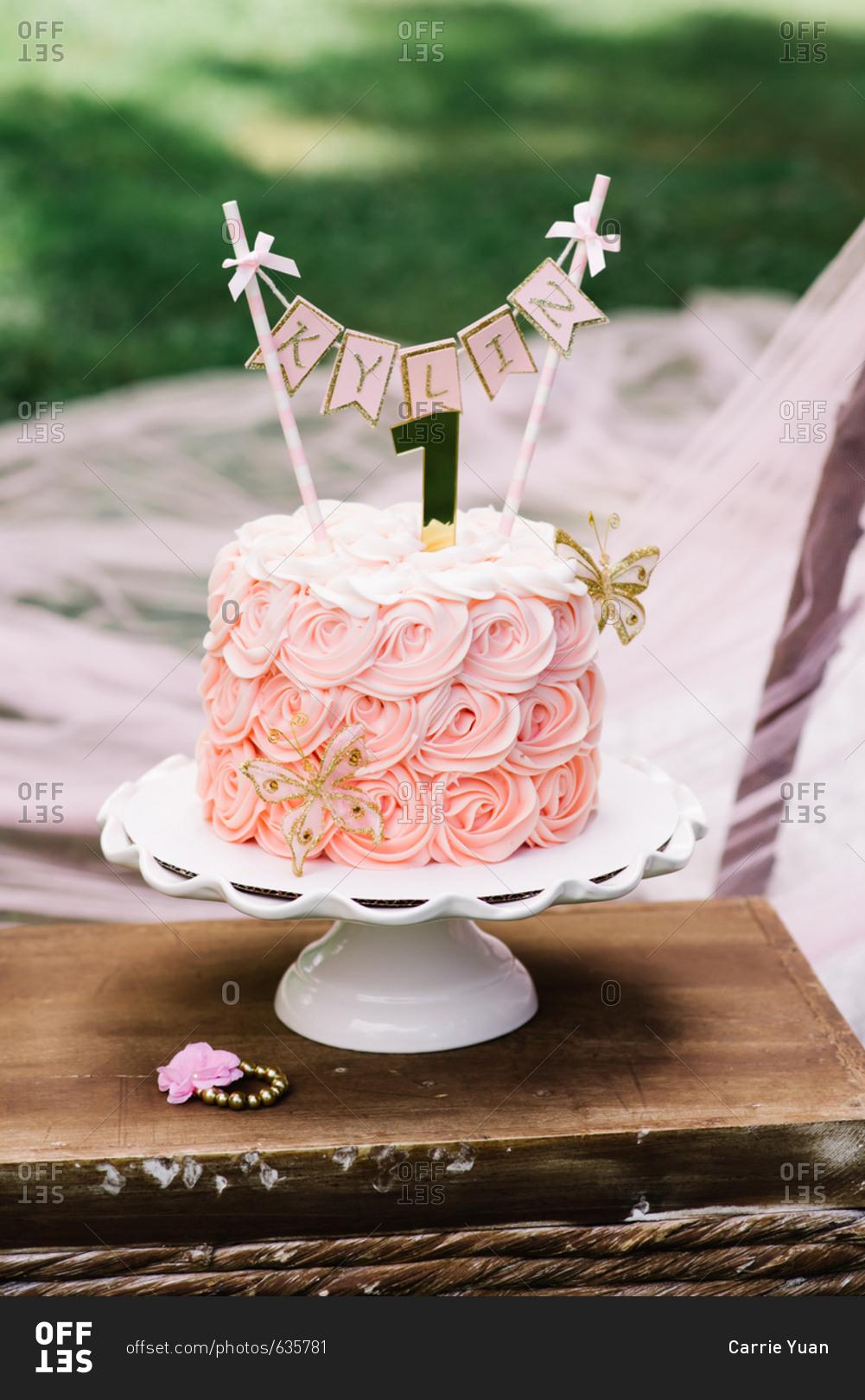 1001x1620 Pink birthday cake celebrating baby's first birthday served on cake stand