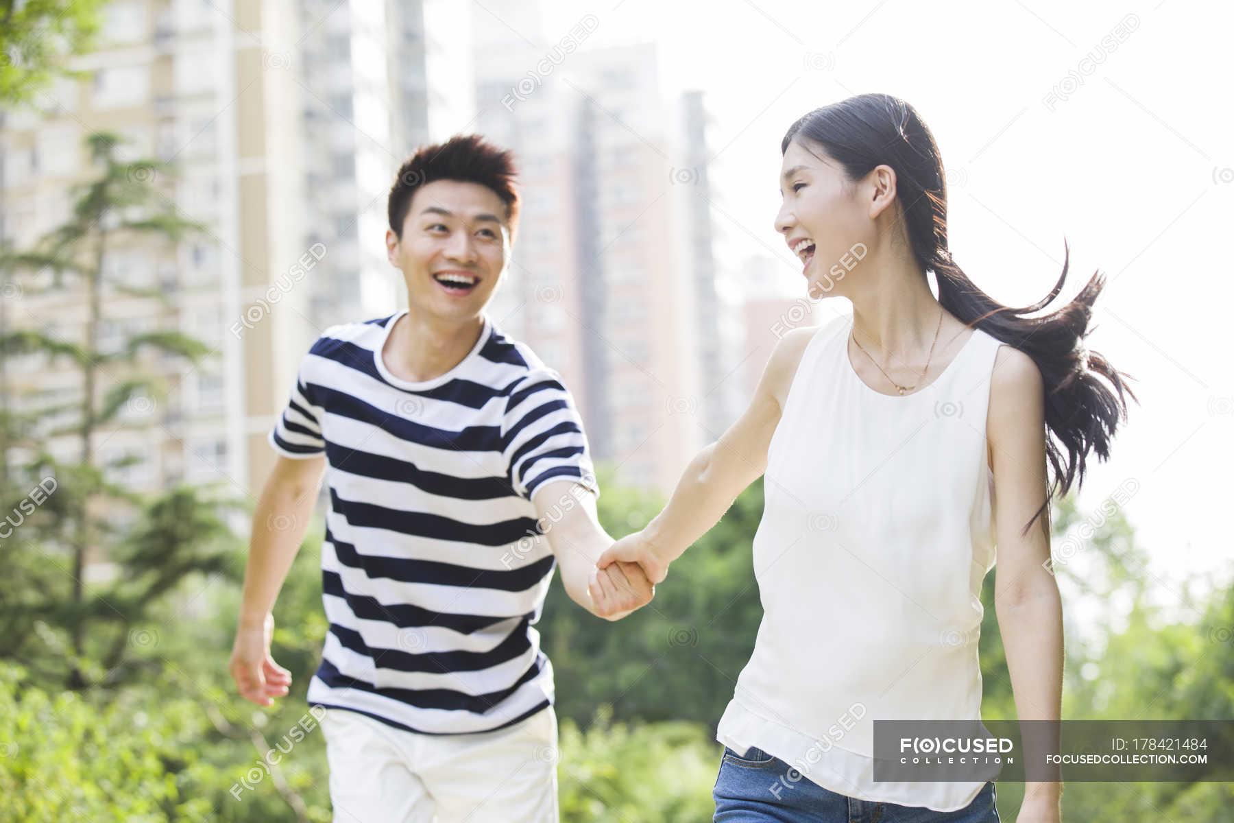 1800x1200 Young Chinese couple holding hands while walking in park