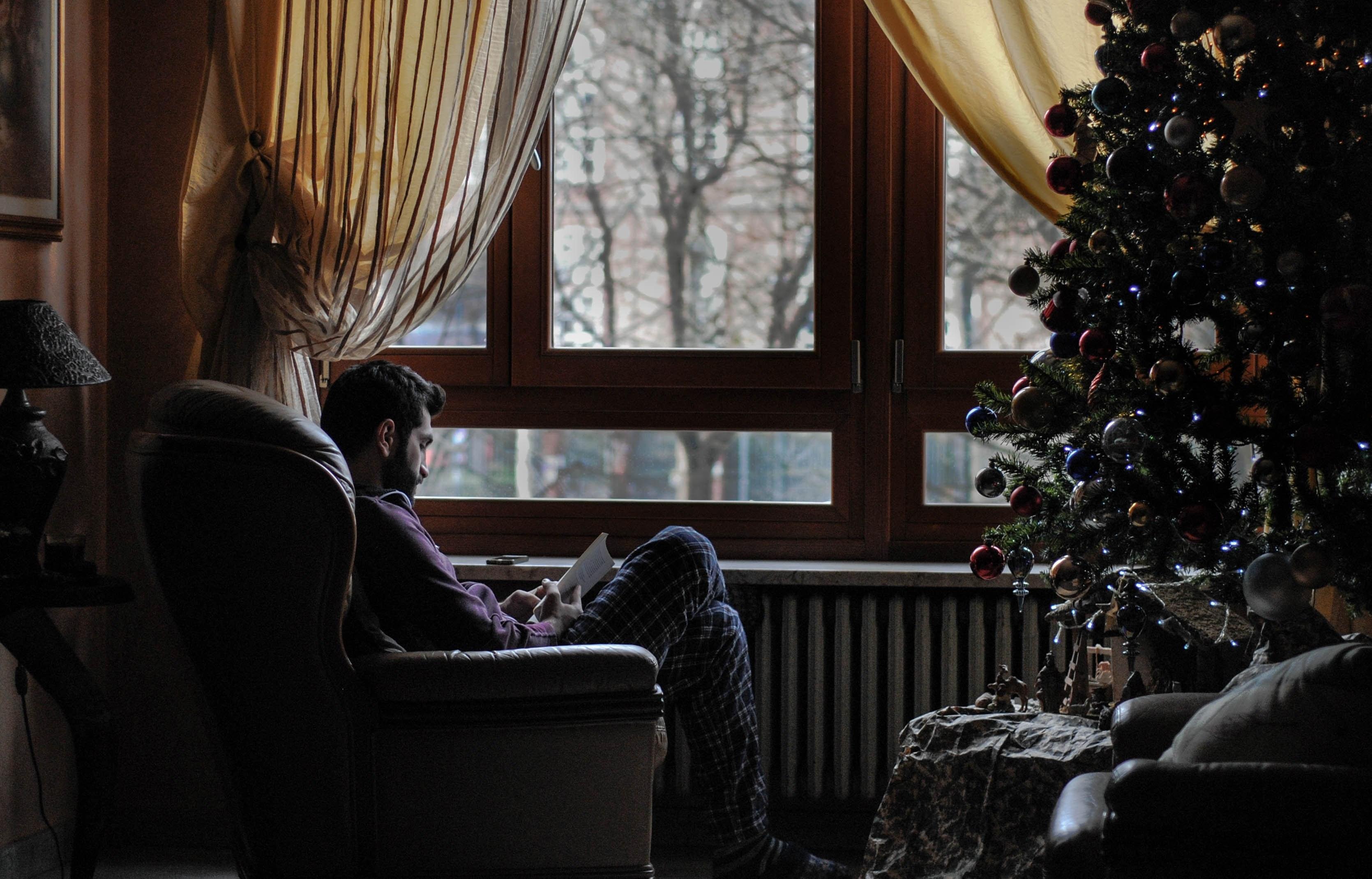 3339x2139 Wallpaper / man reading a book sitting by the window during christmas at metropolitan city of turin, cozy home 4k wallpaper free download