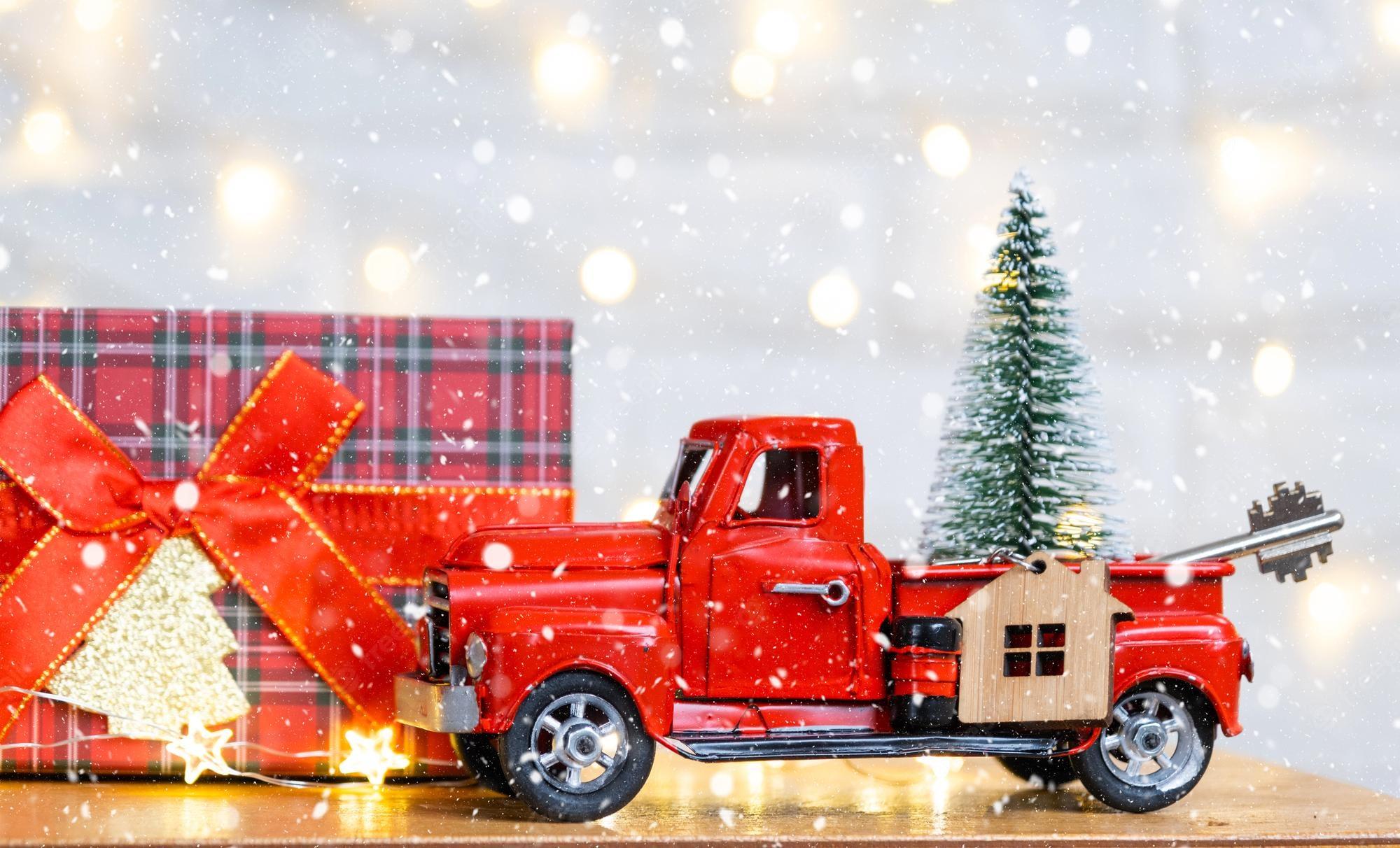 2000x1212 Premium Photo. Red retro car with a christmas tree decorates with the house key in the pickup truck for christmas buying a home moving mortgage loan real estate festive mood new