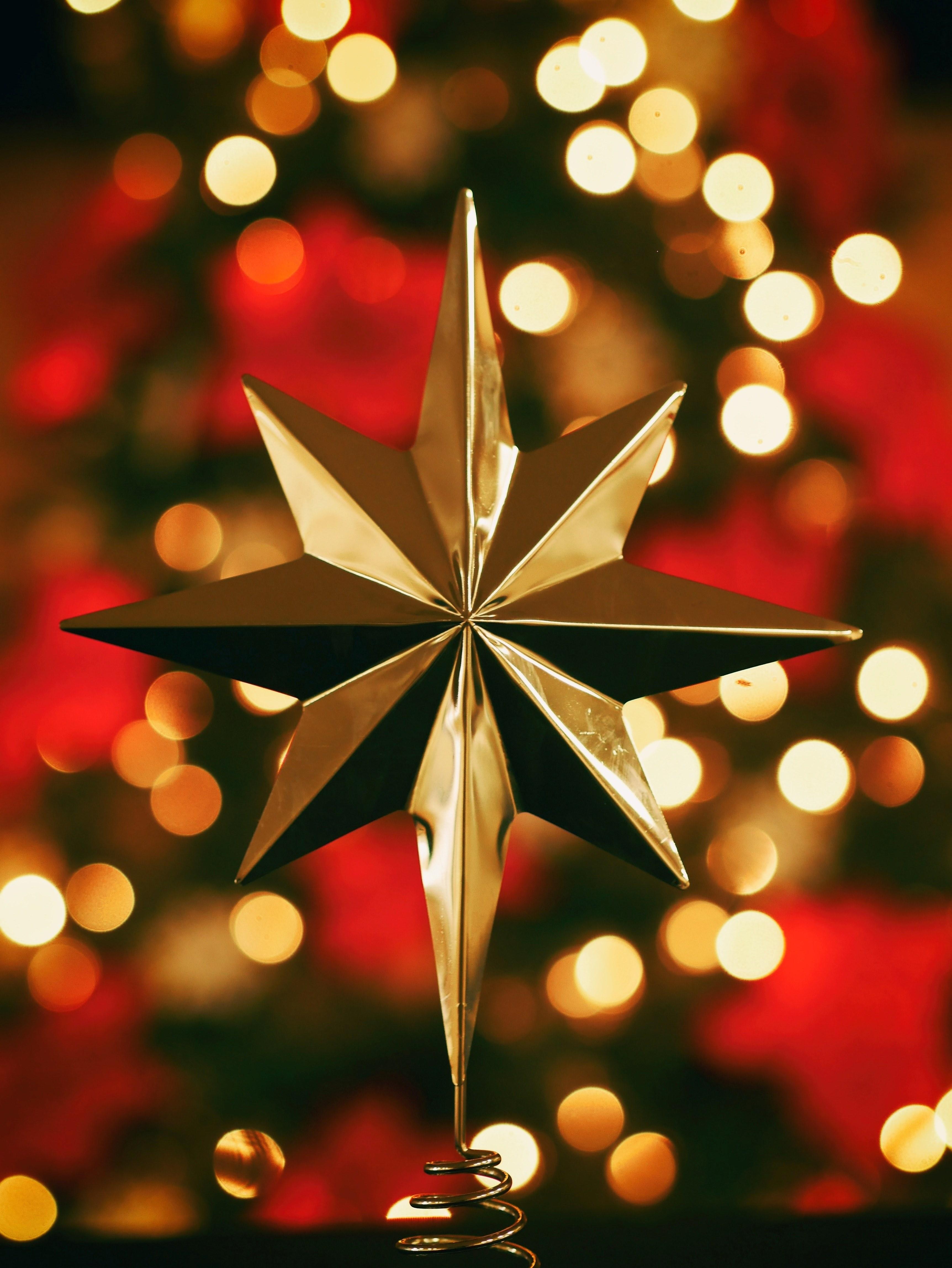 3448x4592 Wallpaper / single gold star in center with unfocused christmas lights and flowers behind at christmastime, christmas star 4k wallpaper free download