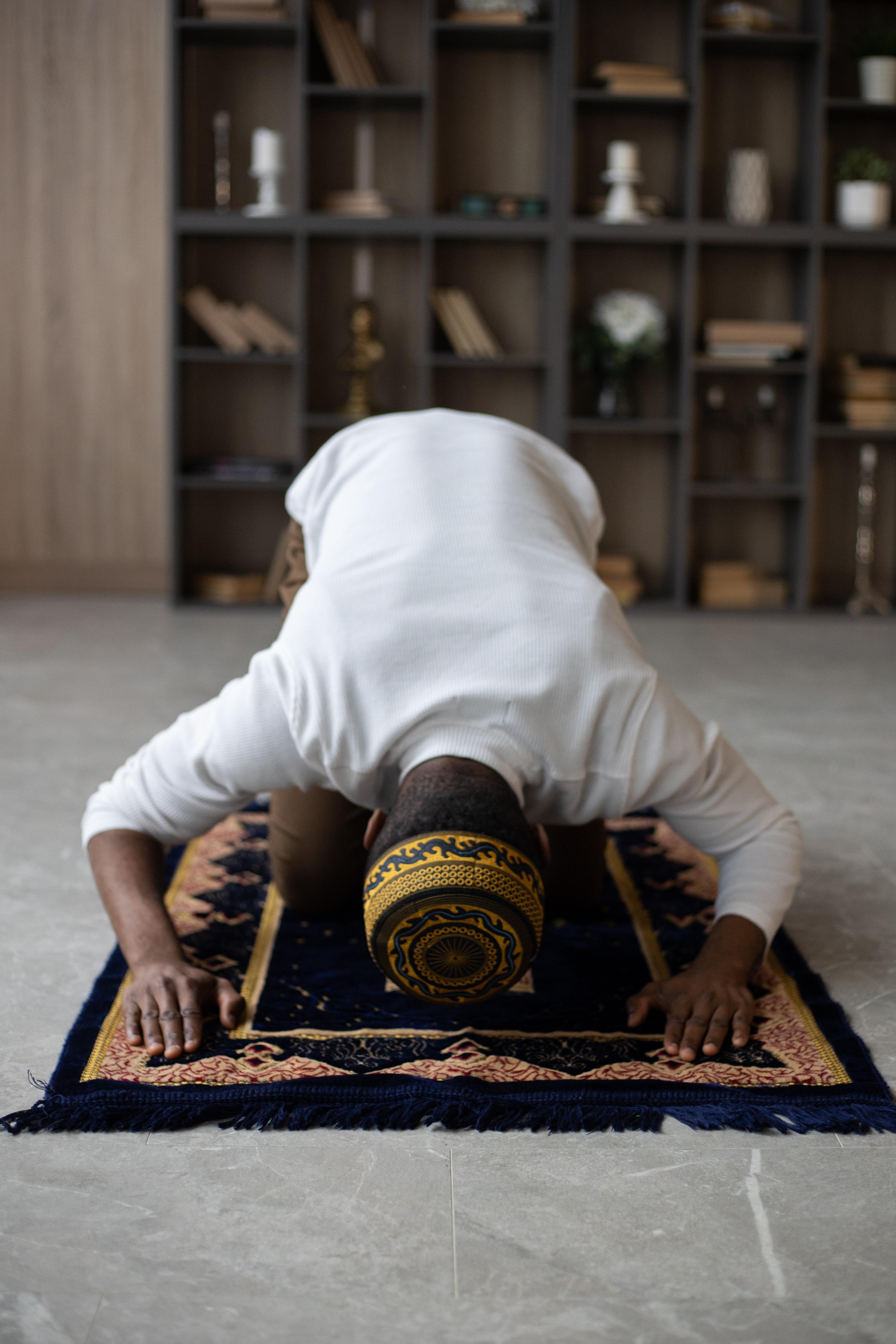 3648x5472 Concentrated black man praying on rug at home · Free