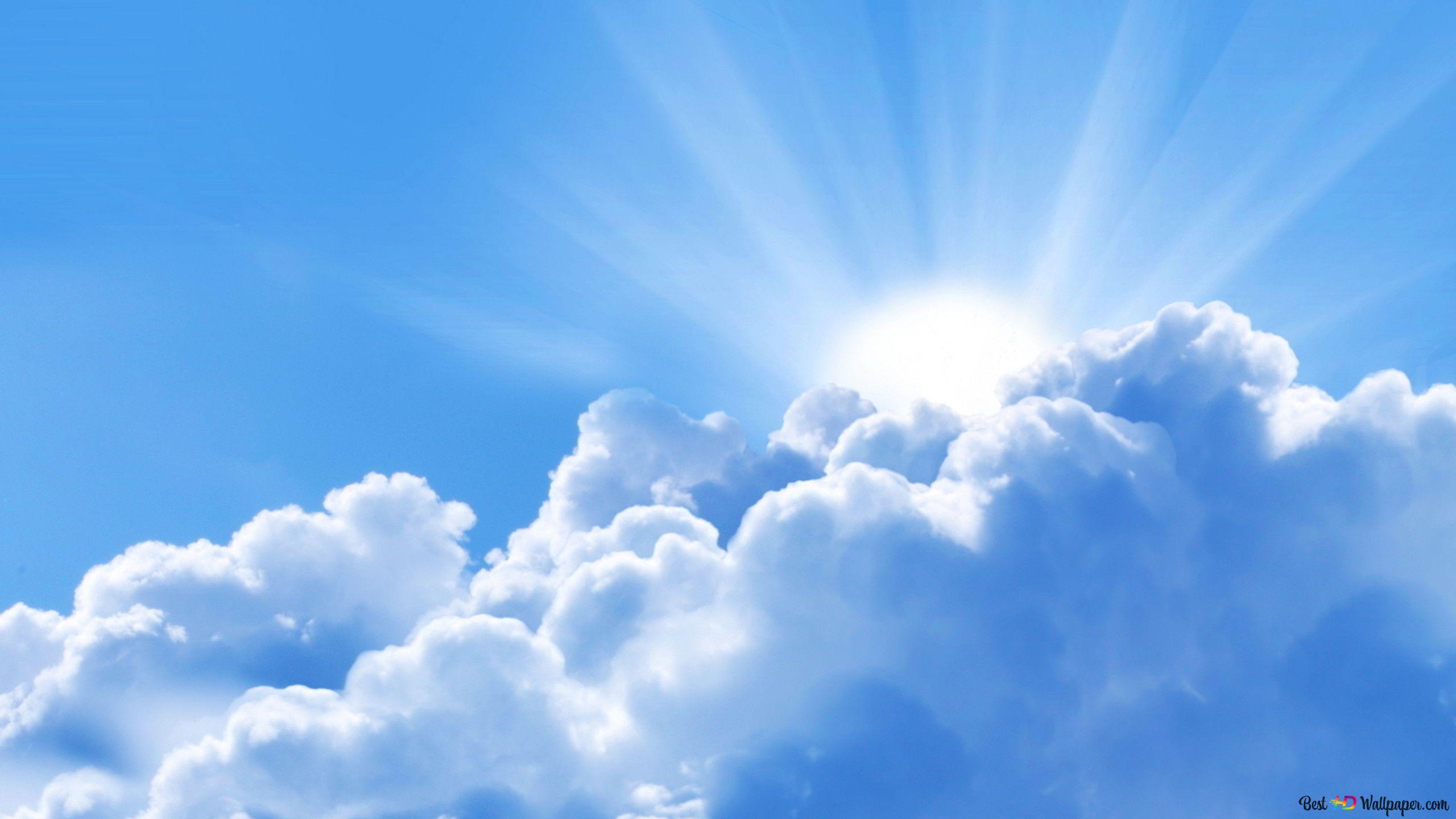 2560x1440 The sun radiating its light behind clusters of white clouds 2K wallpaper download