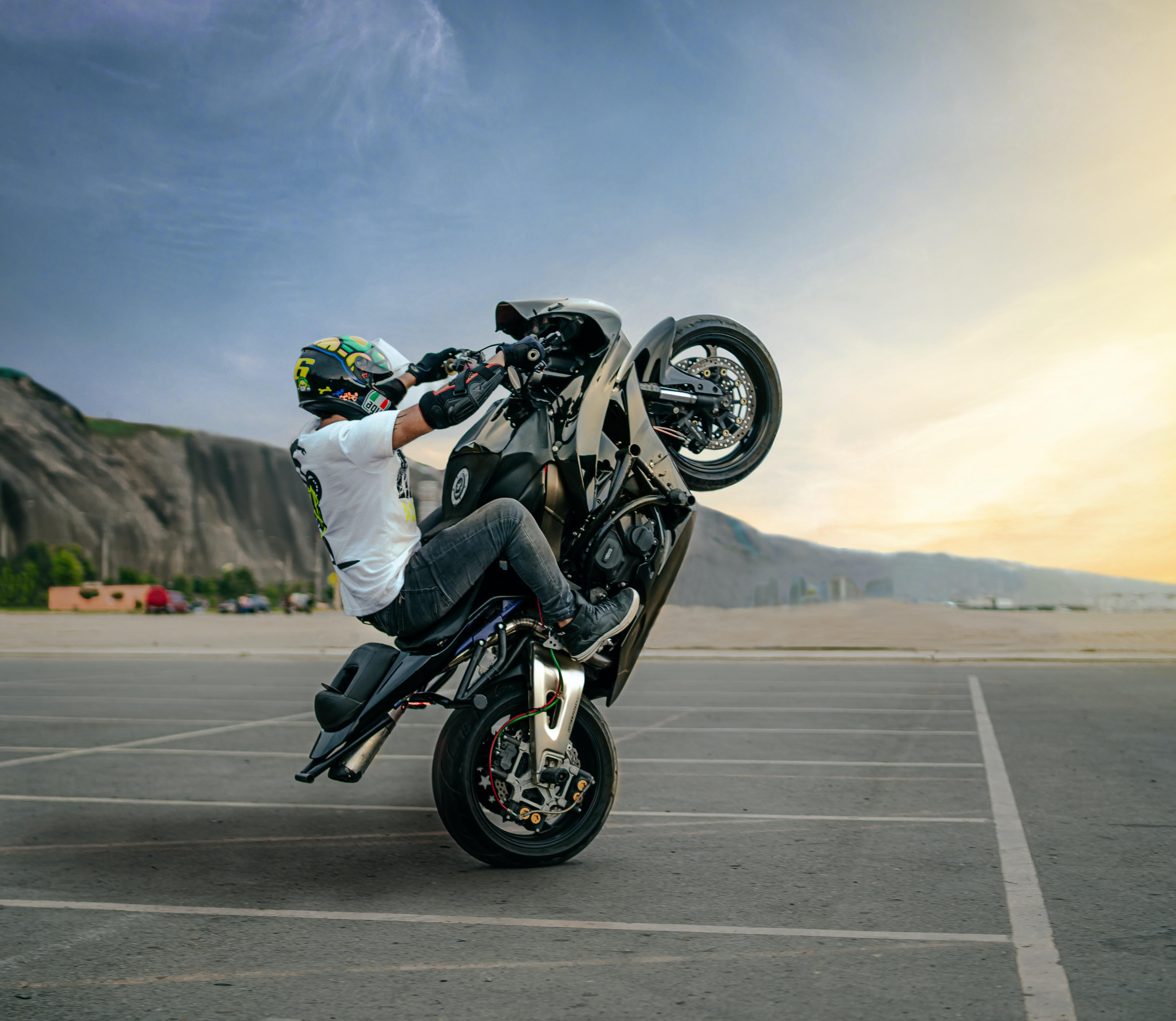 5869x5097 Faceless biker performing trick on motorbike on road · Free