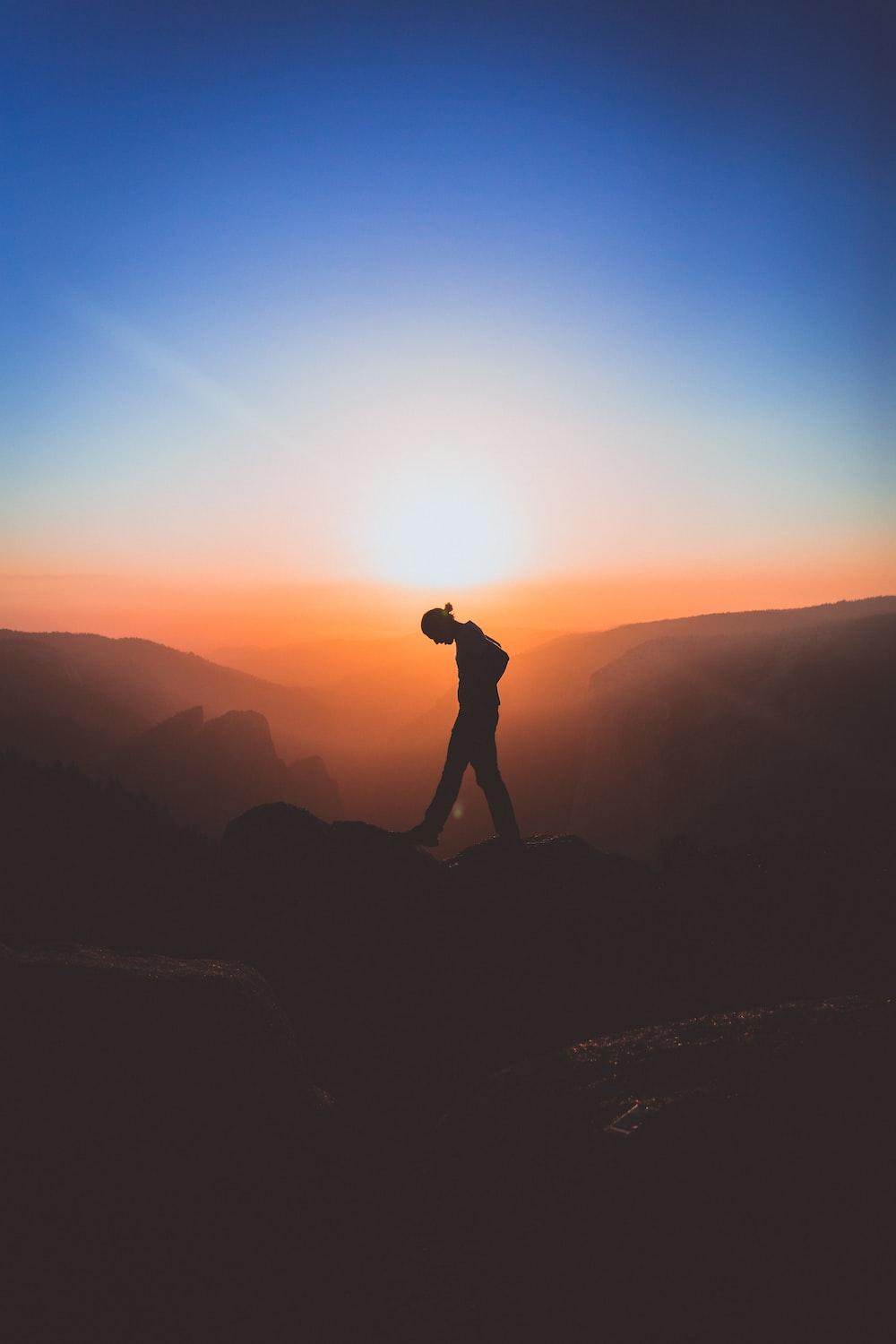 1000x1500 silhouette of man standing on mountain peak photo