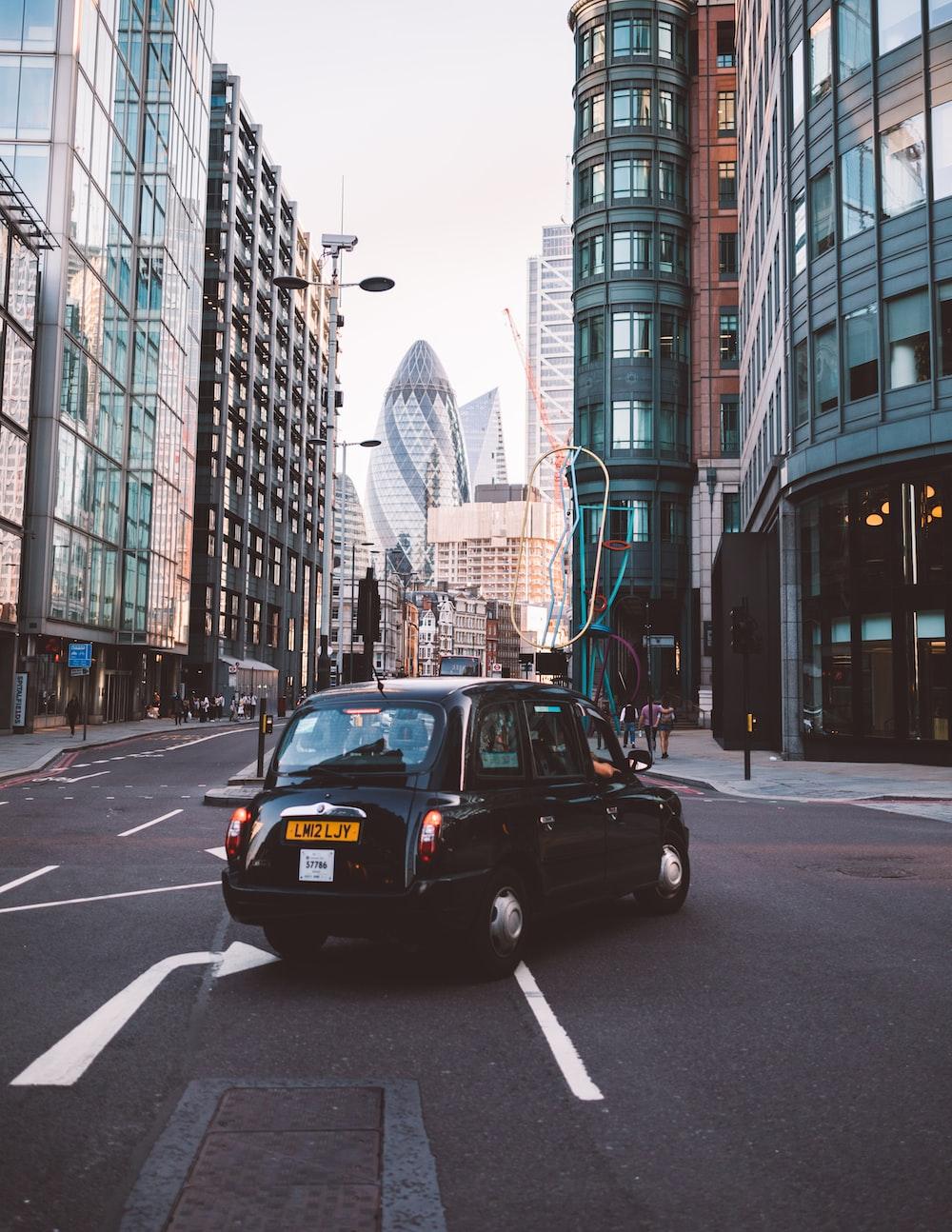 1000x1294 classic black car making right turn beside glass curtain buildings during daytime photo