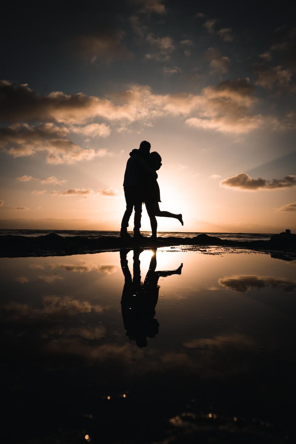 1000x1500 silhouette of man and woman standing on seashore during sunset photo