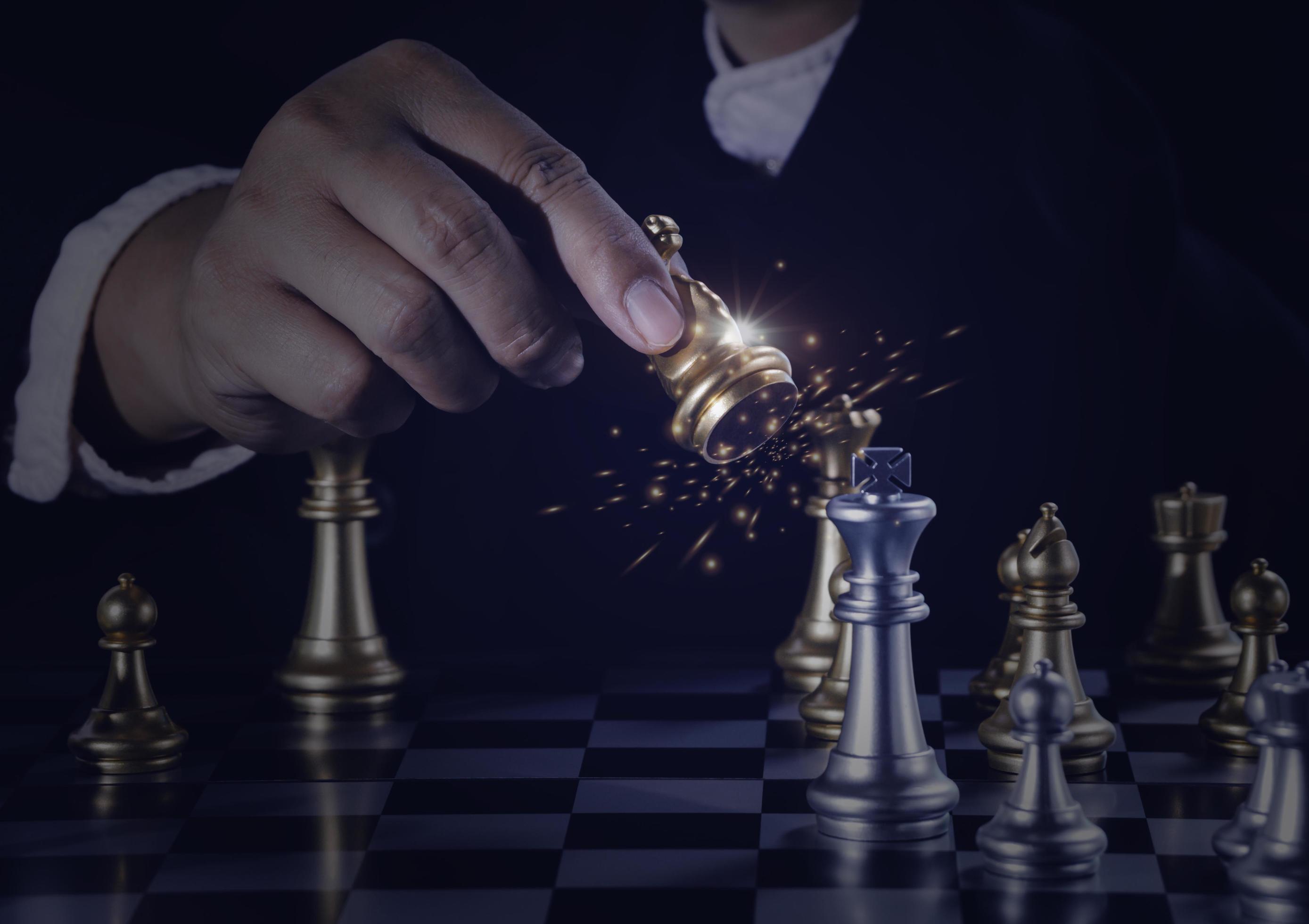 2777x1960 Hand businessman moving the golden knight chess fighting silver knight with fire sparks chess on chess board to successfully in the competition. Management or leadership strategy and teamwork concept. 7869012