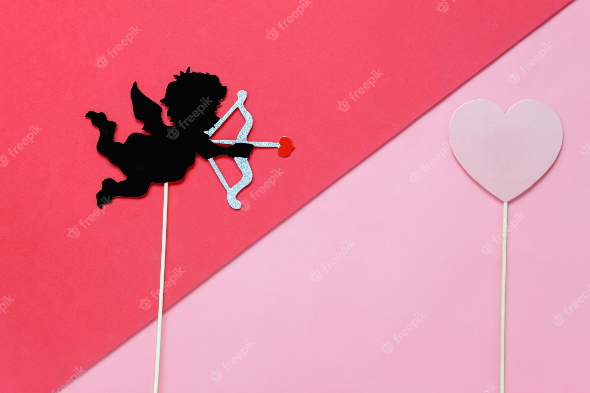 2000x1333 Premium Photo. Diy photo booth props the cupid shoot arrow to red heart on modern rustic pink wallpaper at home office desk studio