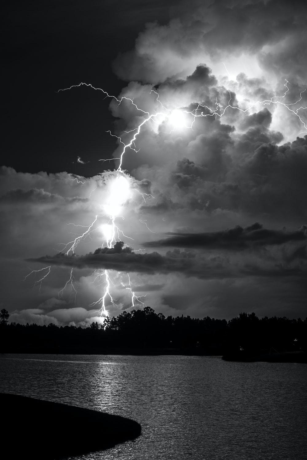 1000x1500 grayscale photo of lightning over body of water photo