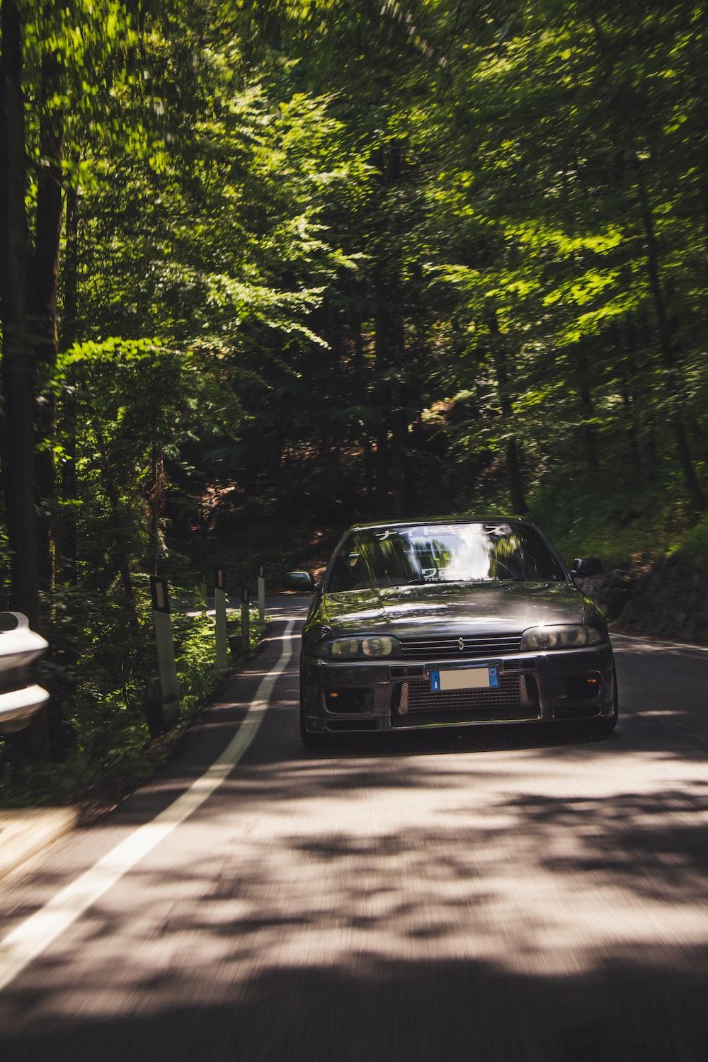 1000x1500 black car on road between trees during daytime photo