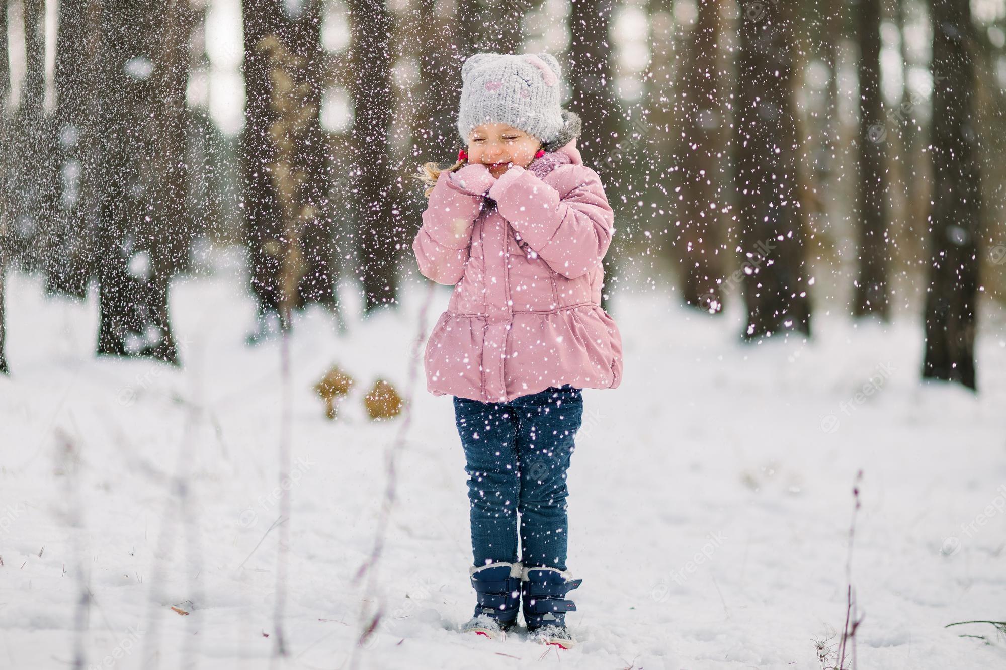 2000x1333 Premium Photo. Let its snow. winter holidays, christmas concept. outdoor portrait of cute little girl enjoying snowfall, while standing with eyes closed in beautiful winter forest
