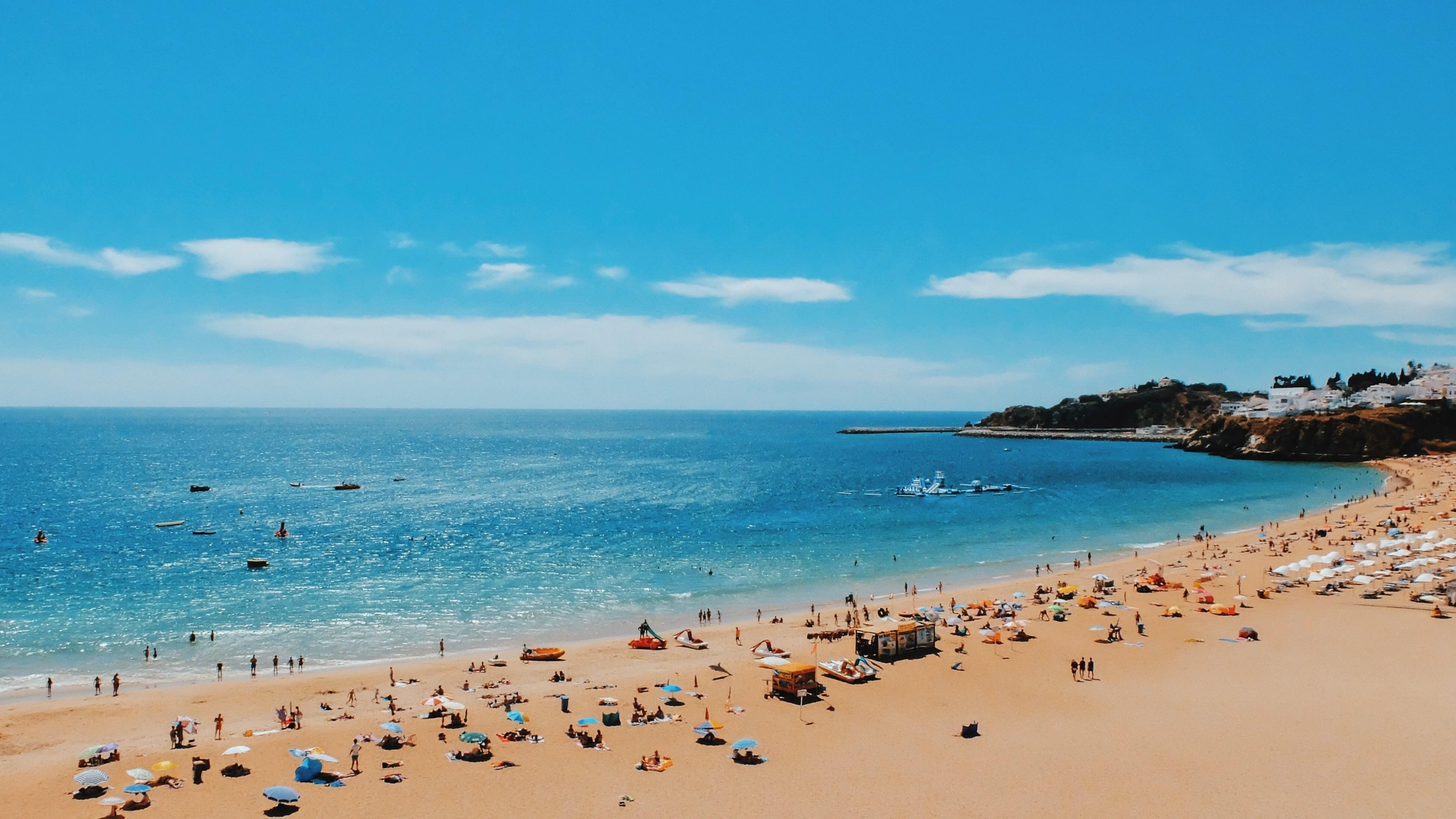 3840x2160 Wallpaper / a crowded beach near a seaside town on a sunny day, tourists on a sandy shore 4k wallpaper free download