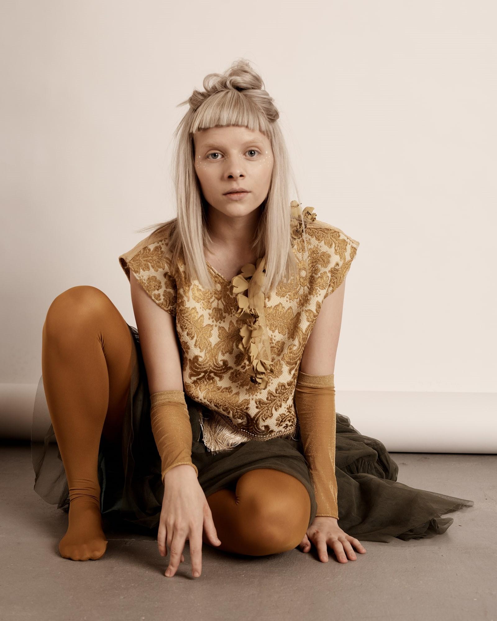 1600x2000 Wallpaper / long hair, hairstyle, depression, blond hair, hand on knee, sitting on floor, looking at camera, beauty, music, Aurora Aksnes, contemplation free download