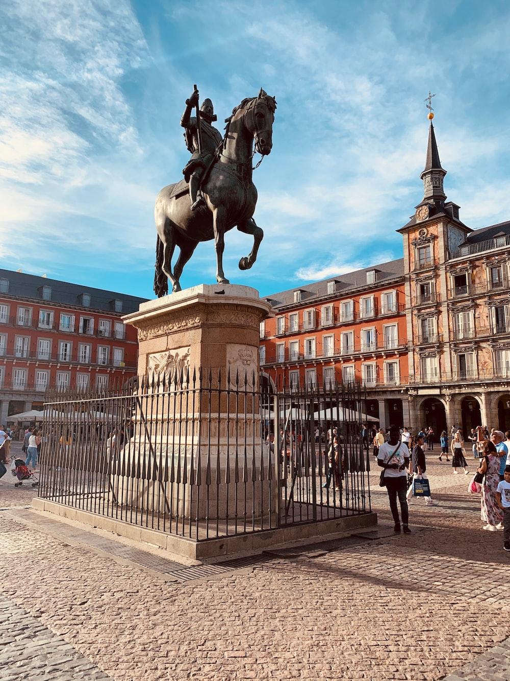 1000x1333 Man riding horse statue on pillar near people and buildings during day photo