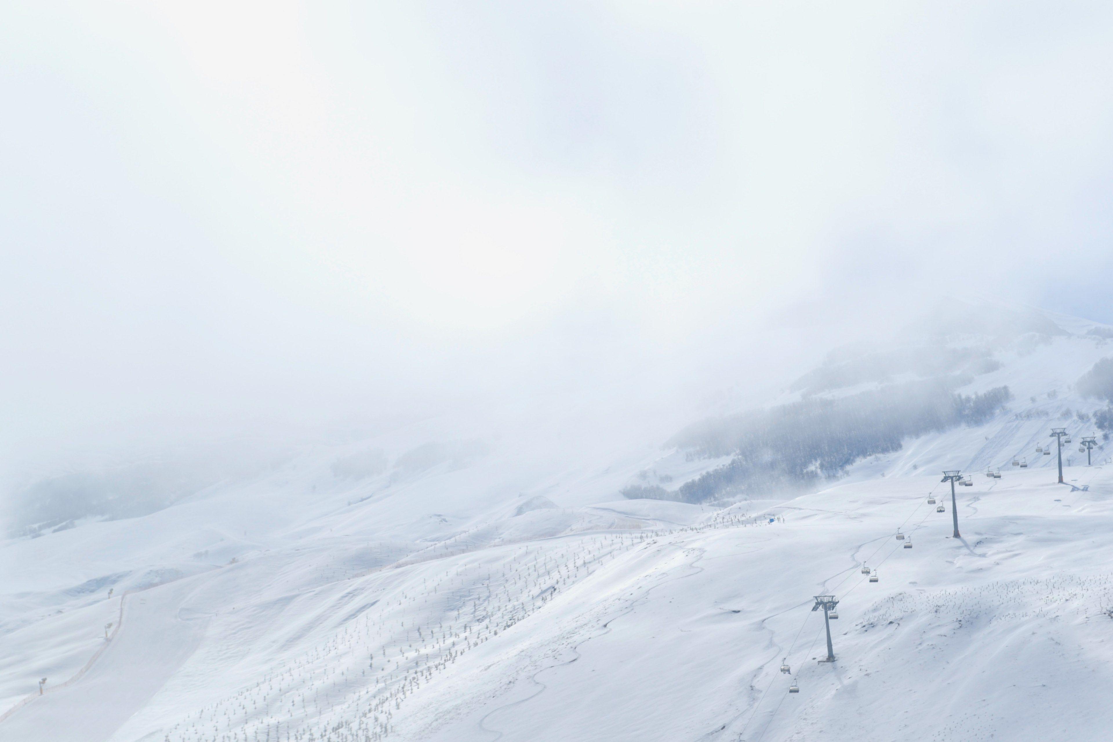 3840x2560 snow covered and foggy mountain side with ski trails and a chairlift