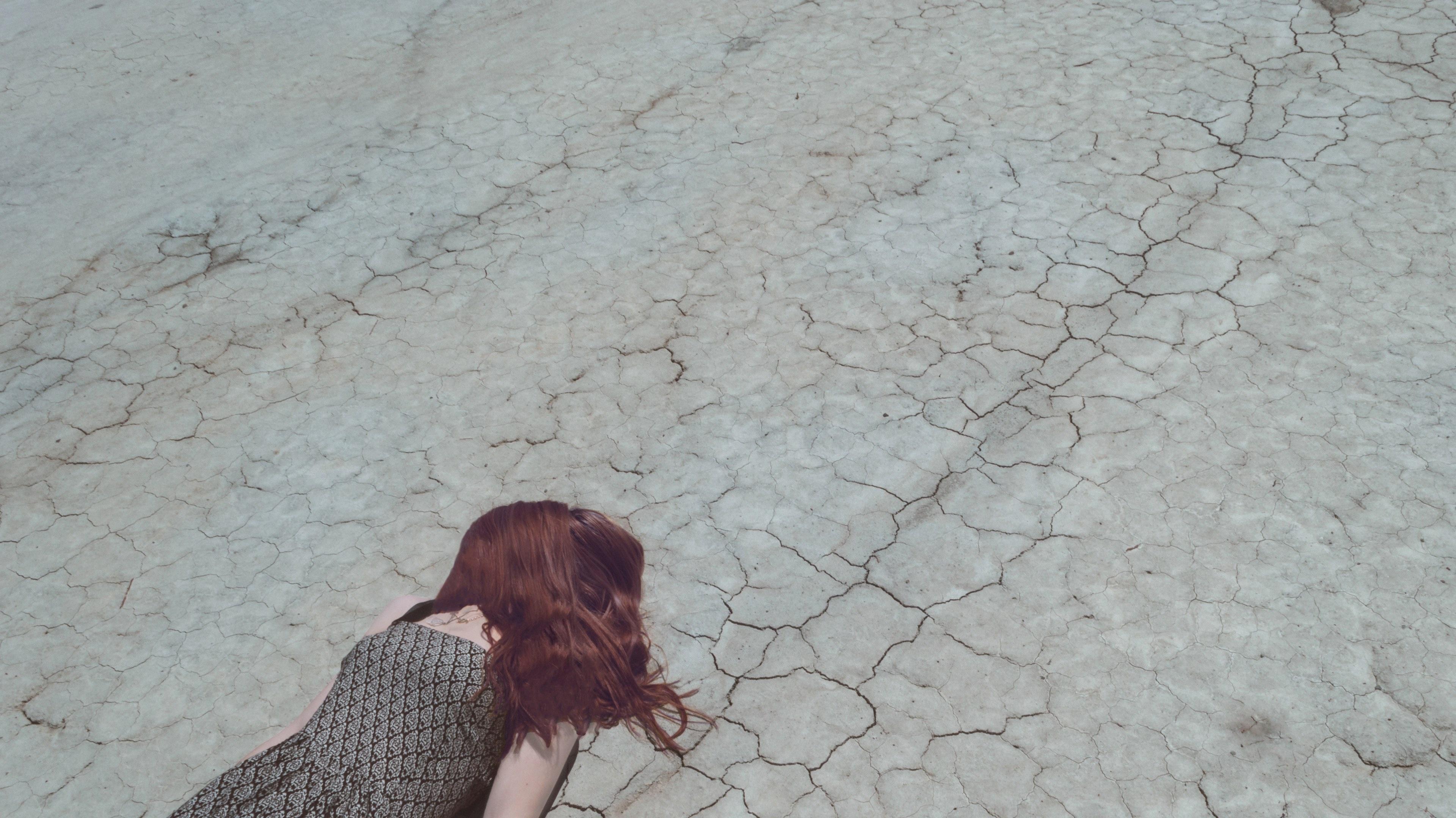 3840x2160 Wallpaper / woman with hair over face lying down on cracked desert floor, exhausted from the heat 4k wallpaper free download