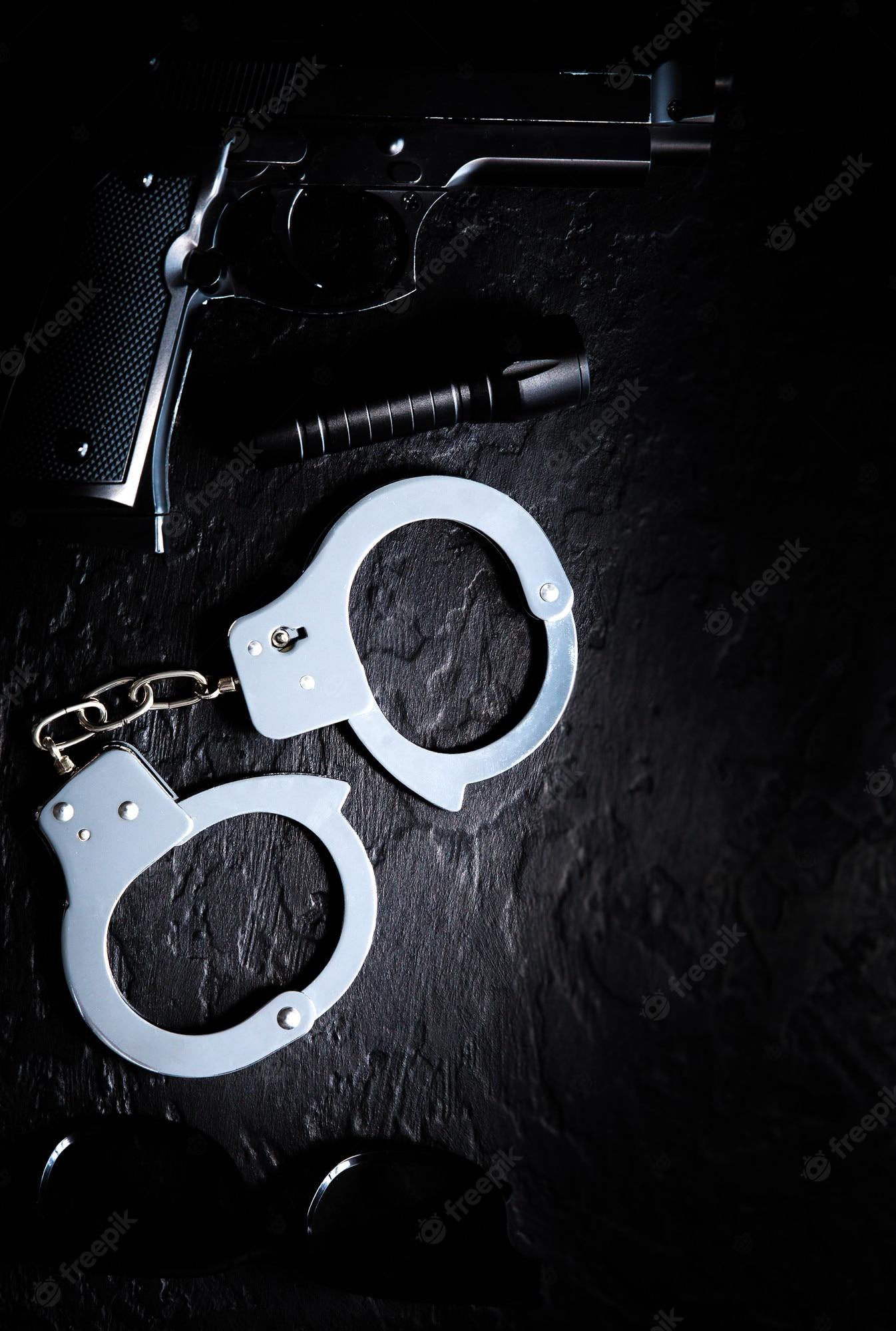 1346x2000 Premium Photo. Black gun, flashlight, glasses and police metal real handcuffs lie on the black background. private detective work. searching information