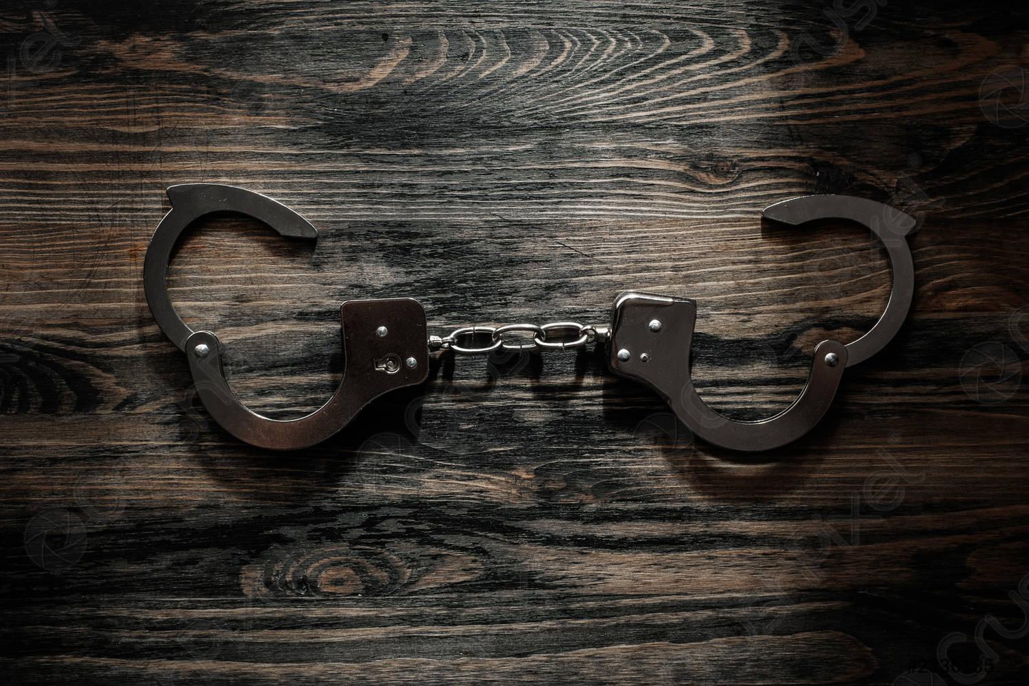 1500x1000 Metal handcuffs on a wooden table