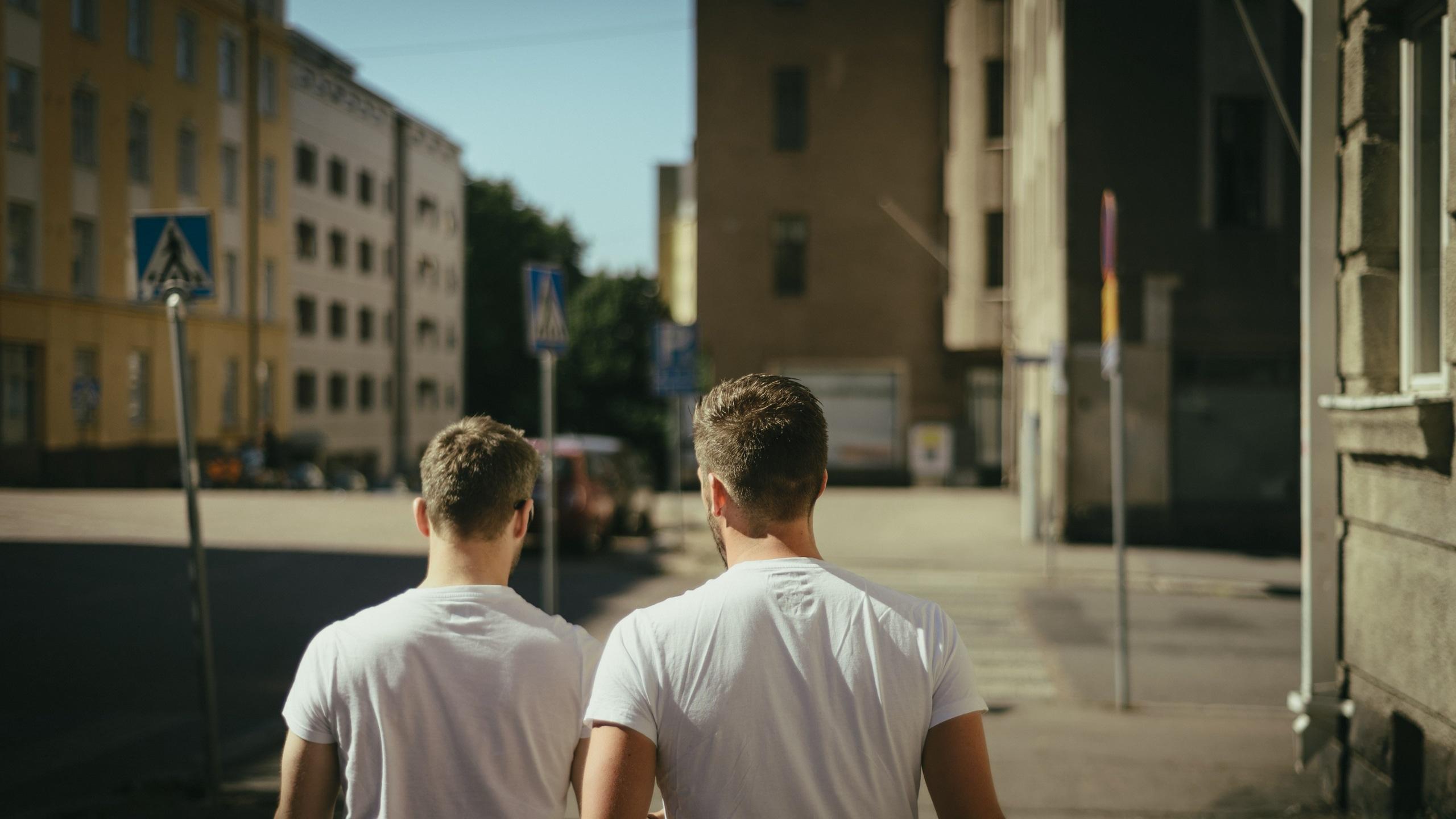 2560x1440 Wallpaper / two men in white t shirts walk away down a city street, walking together 4k wallpaper free download