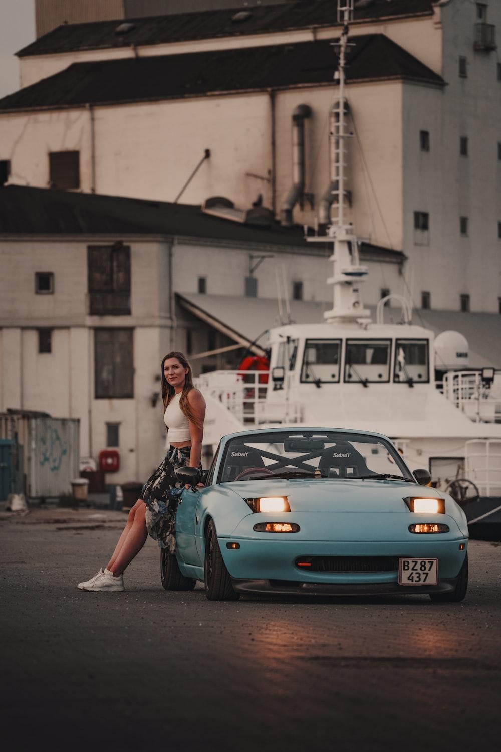 1000x1500 A woman sitting on the hood of a blue car photo