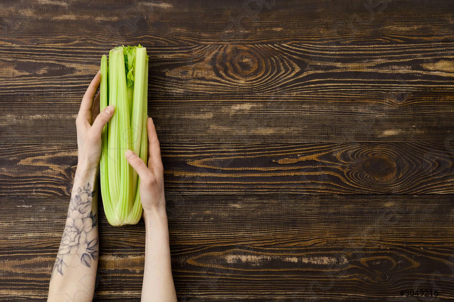 1500x1000 Overhead view of celery in hand over wooden background