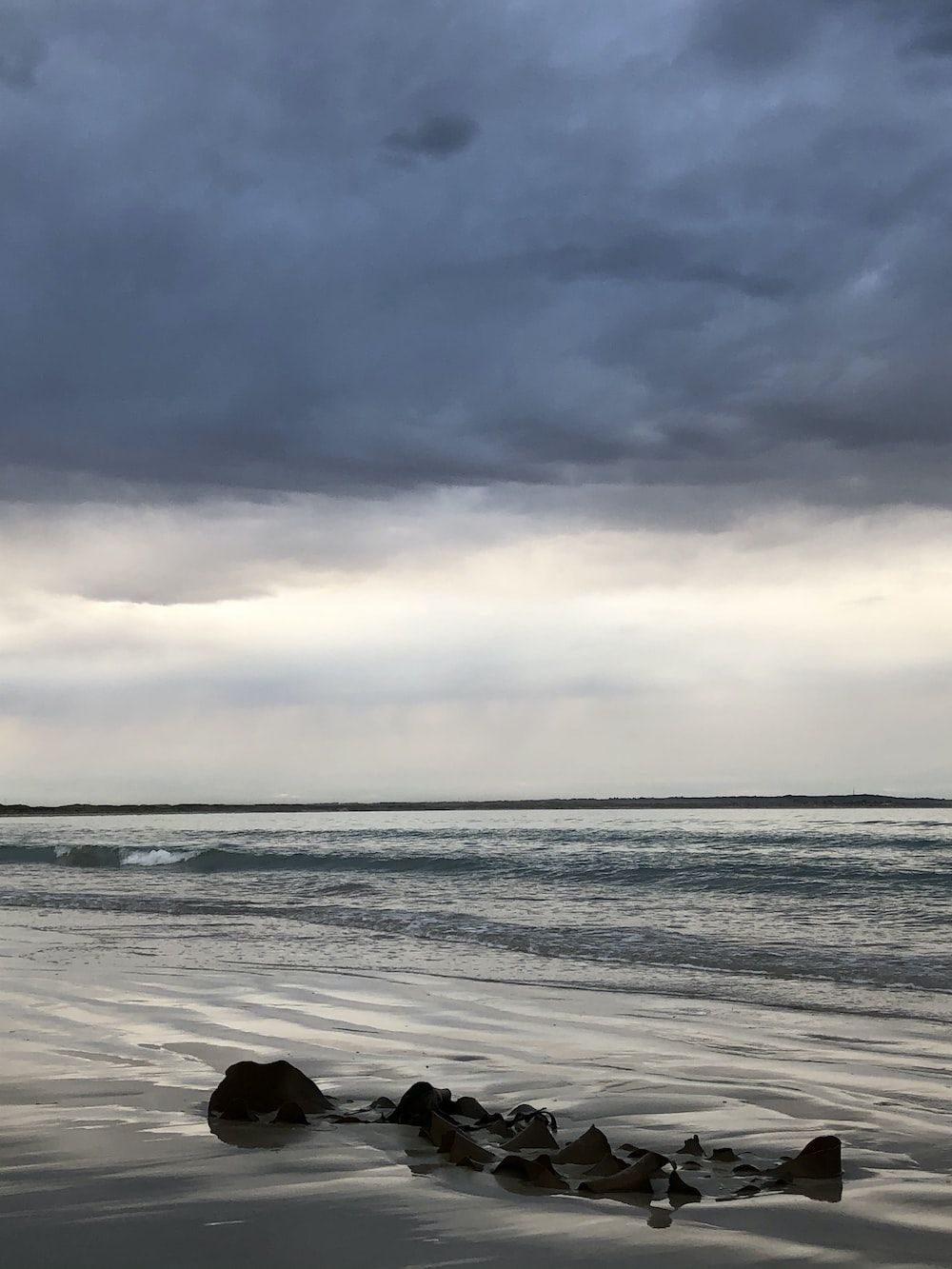 1000x1333 A cloudy day at the beach with rocks in the foreground photo