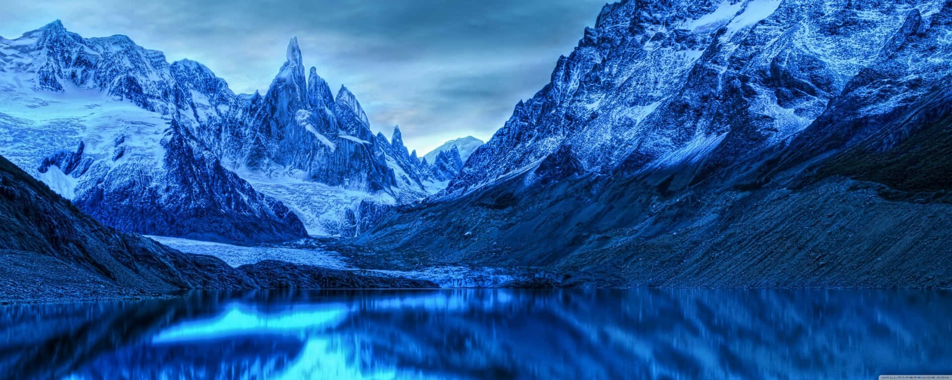 1920x768 Download A Blue Mountain Range With A Lake In The Background Wallpaper